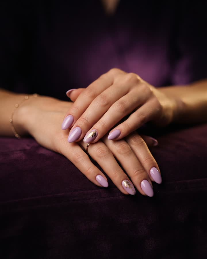 Mãos com unhas em esmalte lilás e detalhe dourado